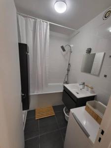 La salle de bains blanche est pourvue d'un lavabo et d'une douche. dans l'établissement Pépite entre Paris et Versailles, à Chaville