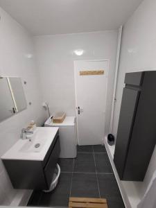 La salle de bains blanche est pourvue d'un lavabo et de toilettes. dans l'établissement Pépite entre Paris et Versailles, à Chaville