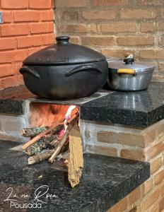 uma panela e frigideiras em cima de uma fogueira em Pousada La na Roça em Paraisópolis