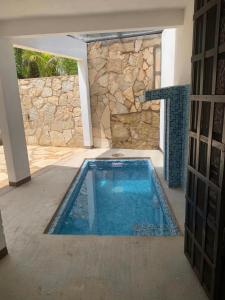 a swimming pool in a house with a stone wall at Cabañas Maya Rue in Palenque
