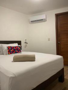 a white bed with a pillow on top of it at Cabañas Maya Rue in Palenque