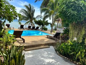 a swimming pool with chairs and the ocean in the background at Phangan Lodge in Ban Tai