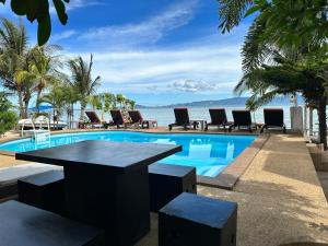 een zwembad met stoelen en een tafel naast de oceaan bij Phangan Lodge in Baan Tai