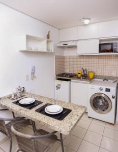 una cucina con tavolo e lavatrice di FLAT PRIVATIVO EQUIPADO WIFI - SUDOESTE a Brasilia