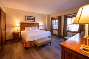 Habitación de hotel con cama, escritorio y ventana en The Lodge at Mountaineer Square en Mount Crested Butte