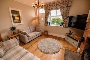 a living room with a couch and a tv at George's Cottage in Bamford