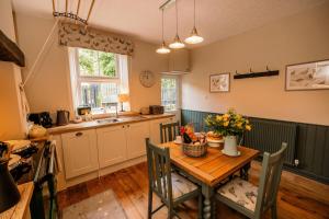a kitchen with a wooden table with flowers on it at George's Cottage in Bamford