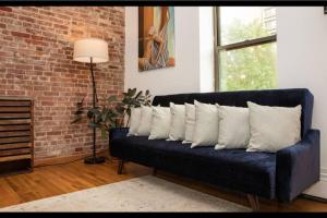 Prime Studio Greenwich Village! في نيويورك: أريكة زرقاء مع وسائد بيضاء في غرفة المعيشة