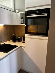 a kitchen with white cabinets and a black microwave at Traumhafter Altbaucharme in zentraler Lage in Kiel