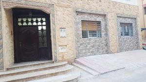 a stone building with a black door and stairs at Appartement familiale méditerranéen in Al Hoceïma