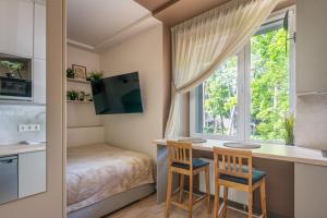 1 dormitorio con escritorio, 2 sillas y ventana en Dzintaru 48 studio, en Jūrmala