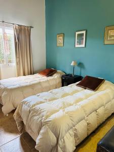 two beds in a room with blue walls at Villa emma in Villa General Belgrano