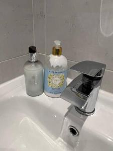 a bathroom sink with a bottle of soap and a faucet at Four Double Bedroom Home - Free parking and Wi-Fi in Horsforth
