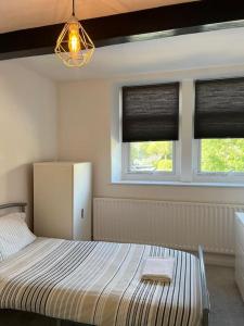 a bedroom with a bed and two windows at Four Double Bedroom Home - Free parking and Wi-Fi in Horsforth