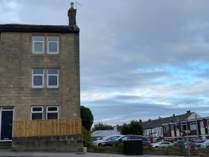 a brick building with cars parked in a parking lot at Four Double Bedroom Home - Free parking and Wi-Fi in Horsforth