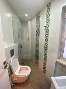 La salle de bains est pourvue d'une douche et de toilettes roses. dans l'établissement No7 Boutique Apartments, à Amman