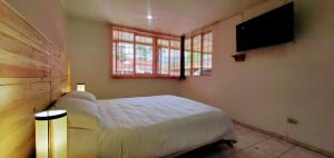a bedroom with a bed and a flat screen tv at Hotel El Gran Chaparral in Calarcá