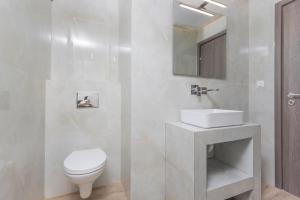 a white bathroom with a toilet and a sink at Lux et Mare in Pefkochori