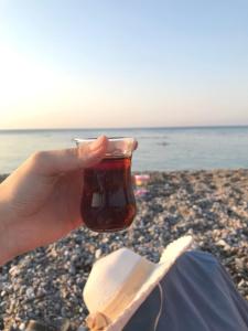 una persona sosteniendo una taza de té en la playa en Beylikduzu Gunluk Kiralik Daire, en Esenyurt