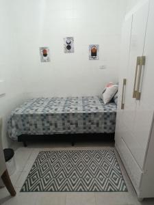 a small bedroom with a bed and a rug at Temporada Paulistana exclusivo para Mulheres in Sao Paulo