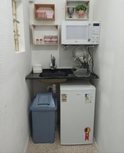 a kitchen with a sink and a microwave and a refrigerator at Temporada Paulistana exclusivo para Mulheres in Sao Paulo
