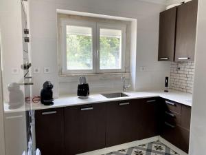 cocina blanca con fregadero y ventana en T2 Alvalade em Lisboa para 3 Pessoas, en Lisboa