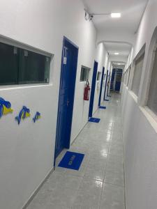 a hallway of a hospital with blue doors and tile floors at Pousada Estação do Porto in Porto De Galinhas