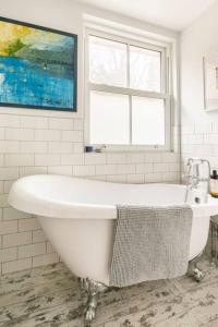 a white bath tub in a bathroom with a window at Hideaway Cottage - seaview room with shared bathroom in Sandgate