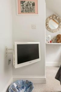 a living room with a tv on the wall at Hideaway Cottage - seaview room with shared bathroom in Sandgate