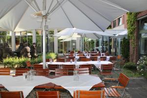 une rangée de tables et de chaises avec des parasols blancs dans l'établissement GenoHotel Forsbach, à Rösrath