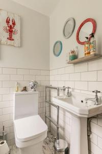 a white bathroom with a toilet and a sink at Hideaway Cottage - seaview room with shared bathroom in Sandgate