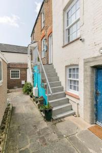 a stairway leading to a building with a blue door at Hideaway Cottage - seaview room with shared bathroom in Sandgate