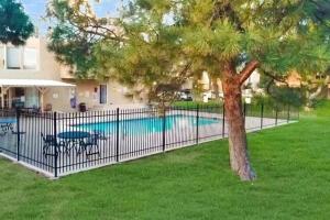 a fence with a tree next to a pool at The Plaza - An Irvie Home w Summer Pool in Albuquerque