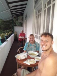 Um homem e uma mulher sentados à mesa com comida. em Kandy Mountain Cottage em Kandy