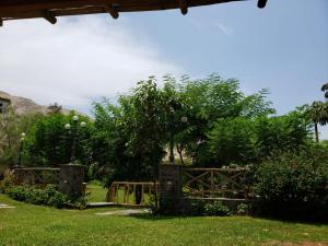 ein Holztor in einem Park mit Bäumen und Gras in der Unterkunft Hacienda Santa María de Cieneguilla in Cieneguilla