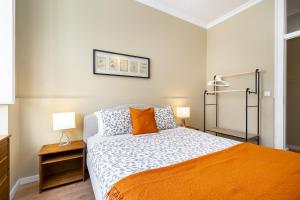 ein Schlafzimmer mit einem Bett mit einer orangefarbenen Decke in der Unterkunft WHome Urban Comfort: 1-BR near Airport & Train Station in Lissabon