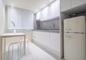 a kitchen with a refrigerator and a table with stools at Osondoson Stay in Seoul