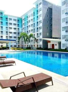 a swimming pool with two benches in front of a building at Jay's Condo - Seawind in Davao City