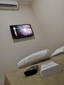 a television on a wall above a bed with a wii controller at POUSADA NOSSO LAR in Guarujá