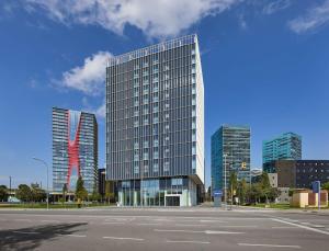 un edificio di vetro alto in una città con parcheggio di Hampton By Hilton Barcelona Fira Gran Via a Hospitalet de Llobregat