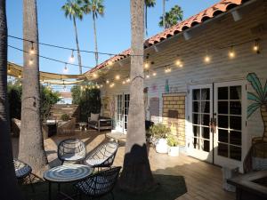 eine Terrasse mit Stühlen, Tischen und Palmen in der Unterkunft The Leta Santa Barbara Goleta, Tapestry Collection by Hilton in Santa Barbara