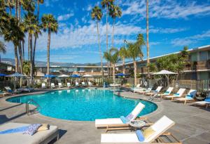 a resort pool with lounge chairs and palm trees at The Leta Santa Barbara Goleta, Tapestry Collection by Hilton in Santa Barbara