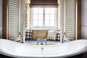 a bathroom with a white tub in front of a window at The Old Stocks Inn in Stow on the Wold
