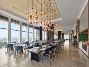 uma sala de jantar com mesas, cadeiras e janelas em Hilton Zhuji em Zhuji