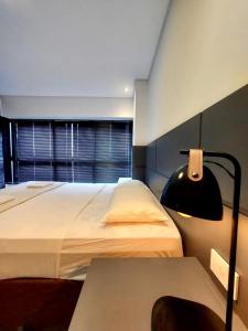 a bedroom with two beds and a lamp and a window at Estúdio Completo e Aconchegante no Ed. Vertigo in Campo Grande