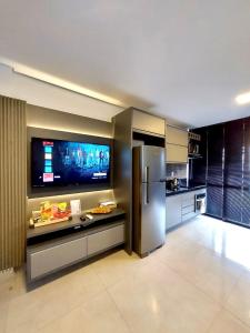 a kitchen with a refrigerator and a flat screen tv at Estúdio Completo e Aconchegante no Ed. Vertigo in Campo Grande