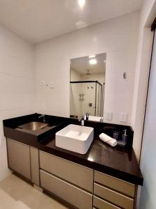 a bathroom with a sink and a large mirror at Estúdio Completo e Aconchegante no Ed. Vertigo in Campo Grande