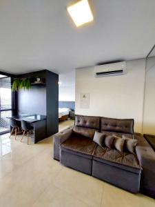 a living room with a brown leather couch and a table at Estúdio Completo e Aconchegante no Ed. Vertigo in Campo Grande +18 photos