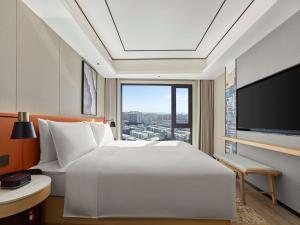 鞍山的住宿－鞍山海城希尔顿花园酒店，卧室设有一张白色大床和大窗户