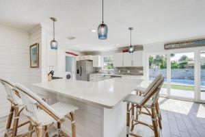 a kitchen with a white counter and chairs at Modern Coastal Home with Pool Mins to Beach and Mayo! in Jacksonville Beach
